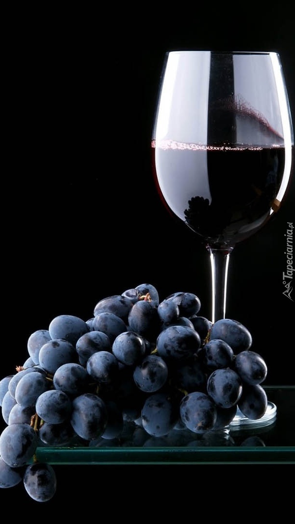 Kieliszek czerwonego wina i ciemne winogrona