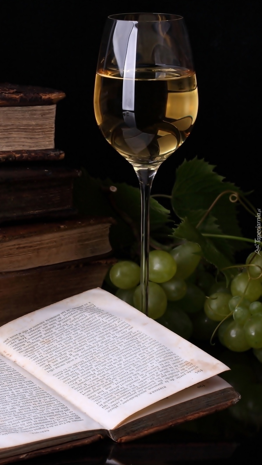 Kieliszek wina obok winogron i książki