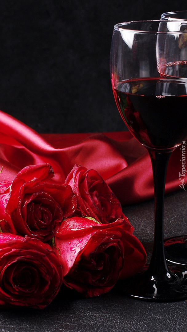 Kieliszki z czerwonym winem obok róż