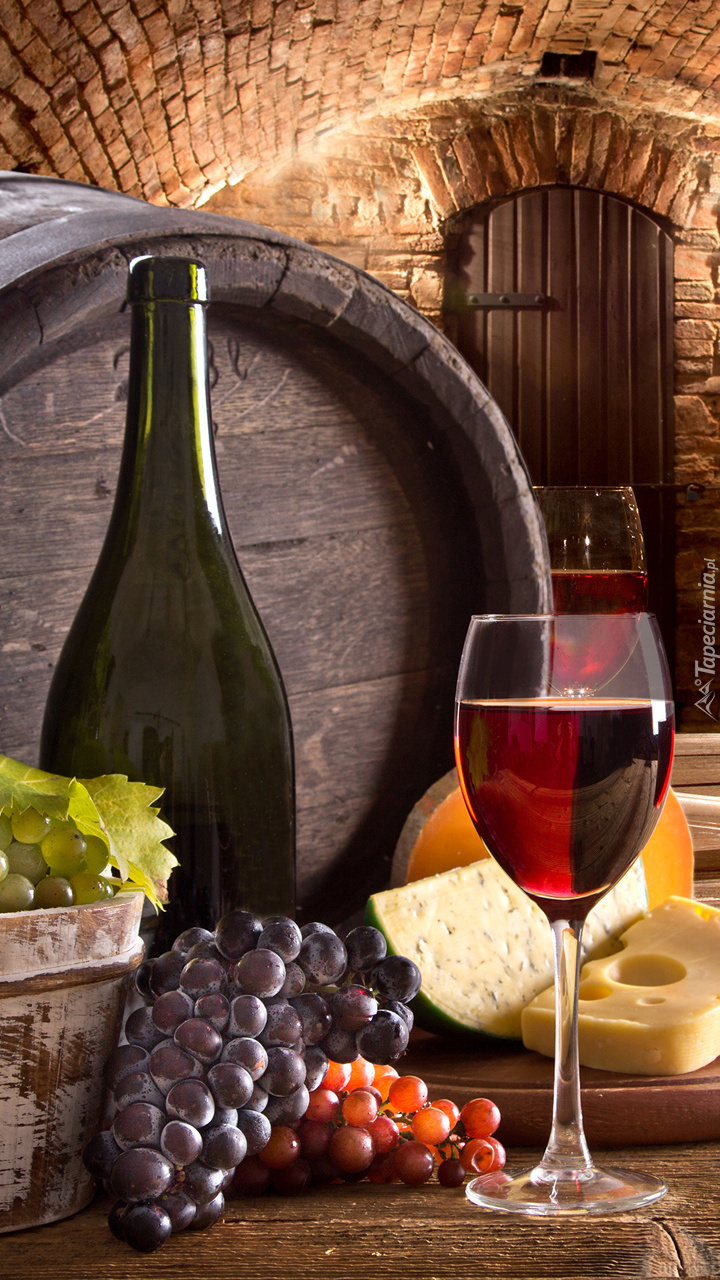 Kiście winogron obok kieliszka i butelki  z winem