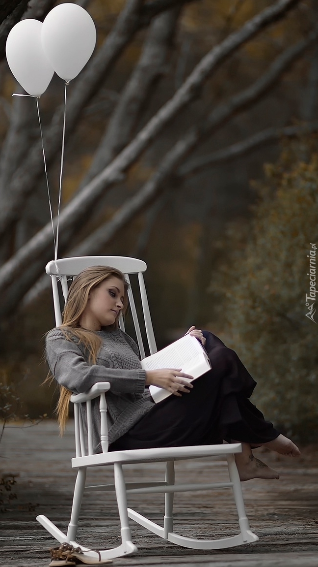 Kobieta na fotelu czytająca ksiażkę