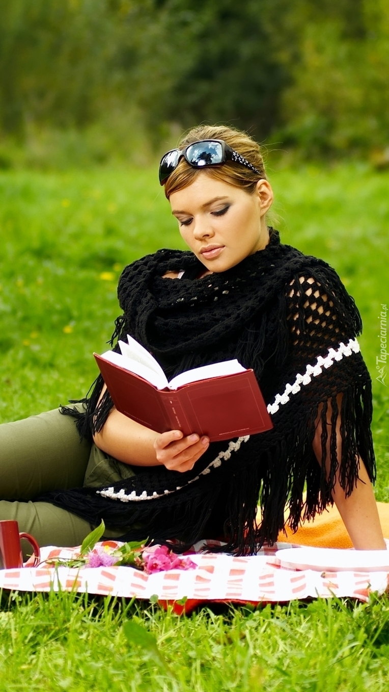 Kobieta na łące czytająca książkę