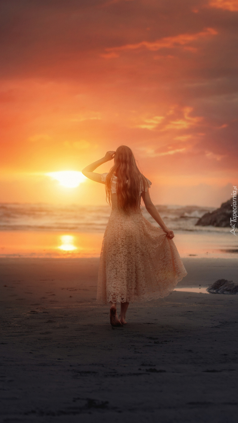 Kobieta na plaży w zachodzącym słońcu