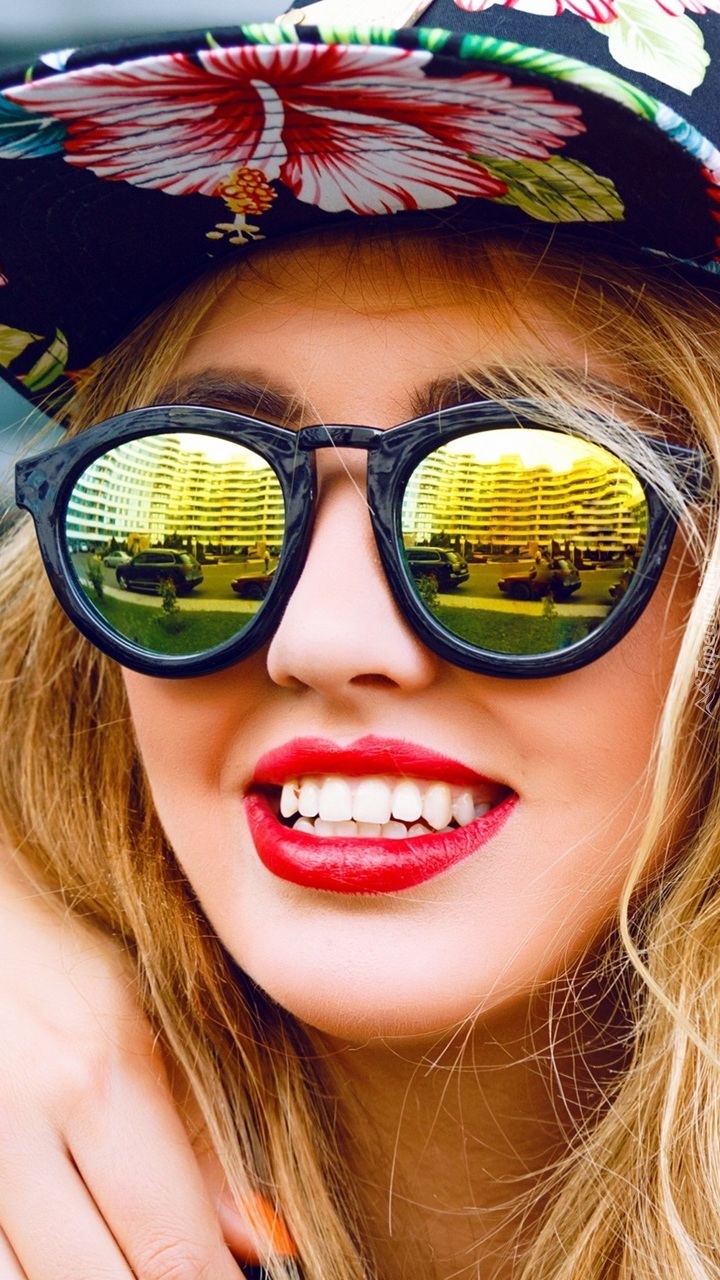 Kobieta o czarującym uśmiechu w czapce i modnych okularach