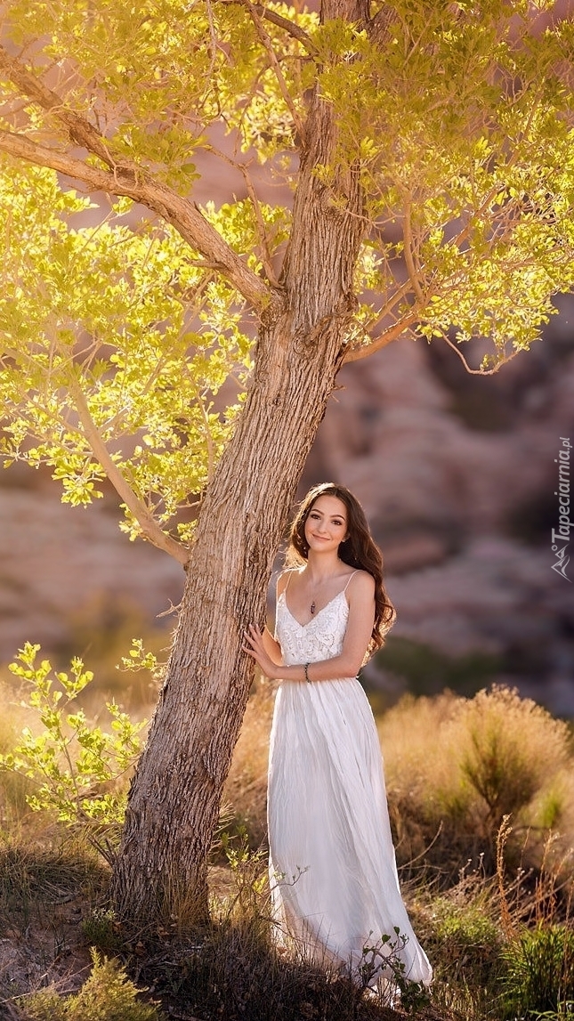 Kobieta pod drzewem w białej sukience