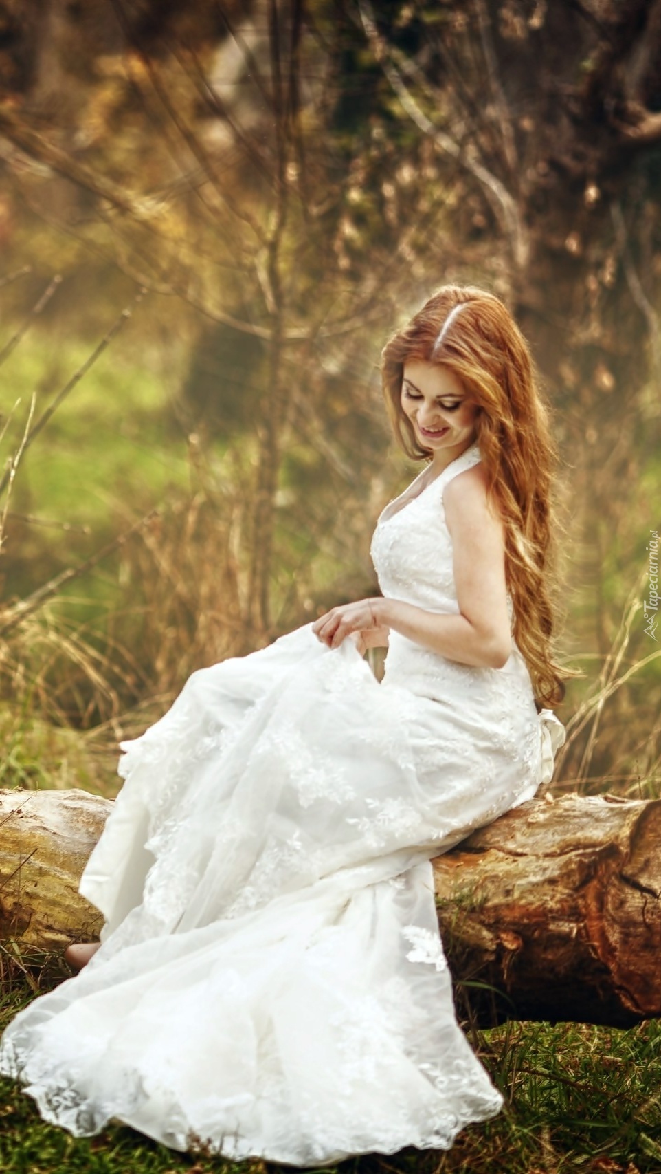 Kobieta w białej sukni siedząca na pniu