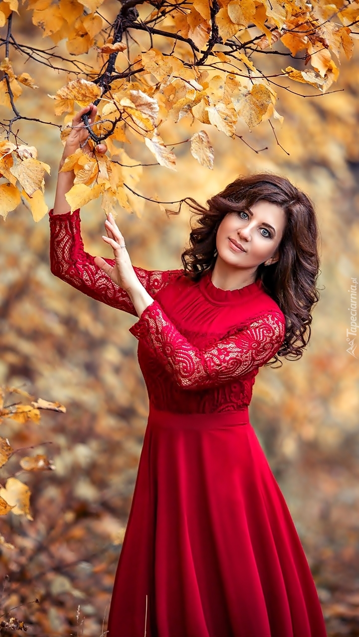 Kobieta w czerwonej sukni w jesiennym parku