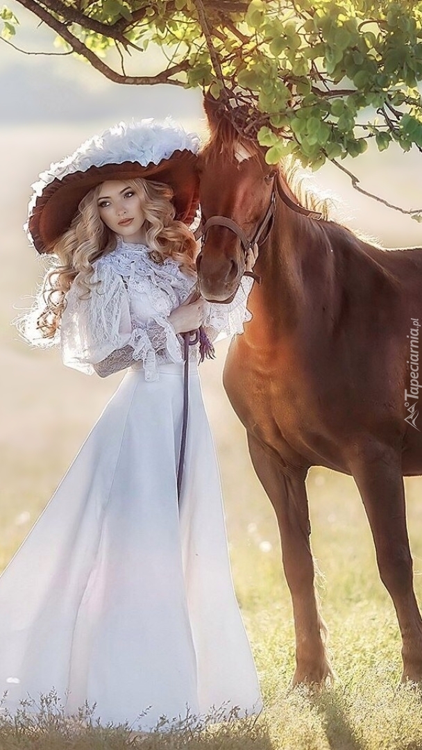 Kobieta w kapeluszu na spacerze z koniem