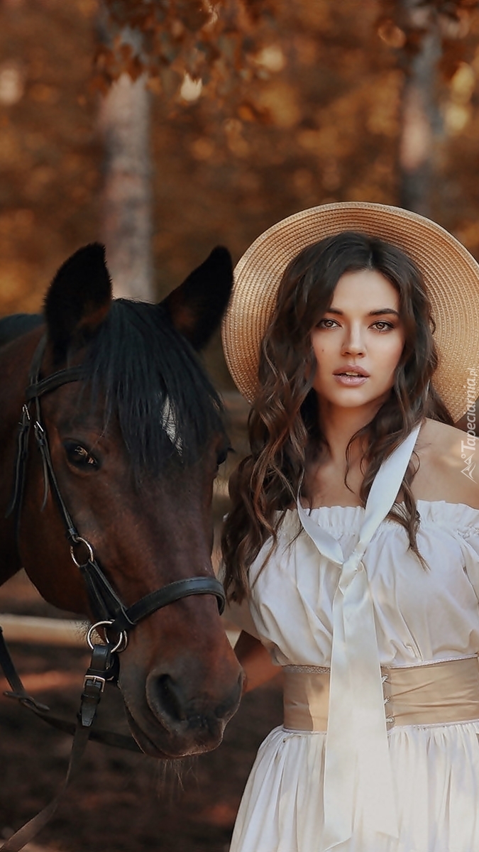 Kobieta w kapeluszu obok konia