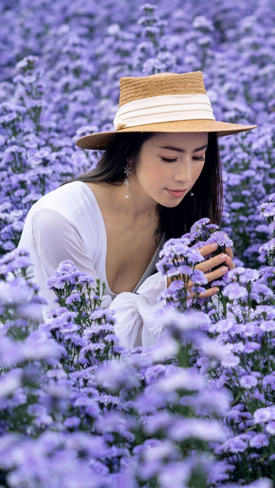 Kobieta w kapeluszu wśród niebieskich kwiatów