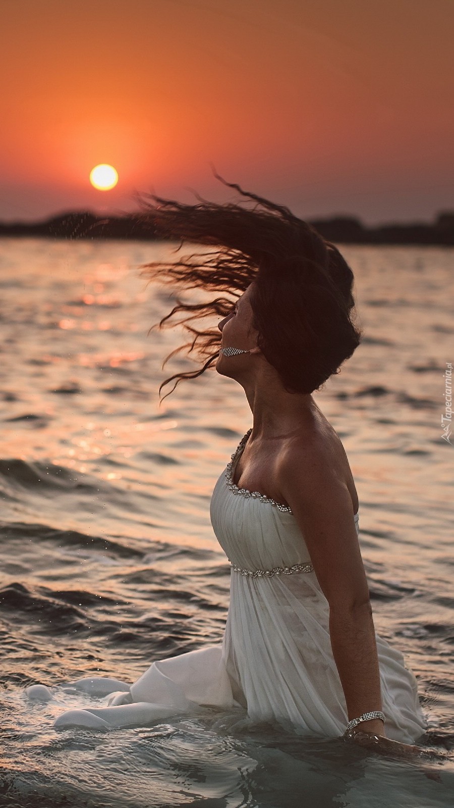 Kobieta w morzu o zachodzie słońca