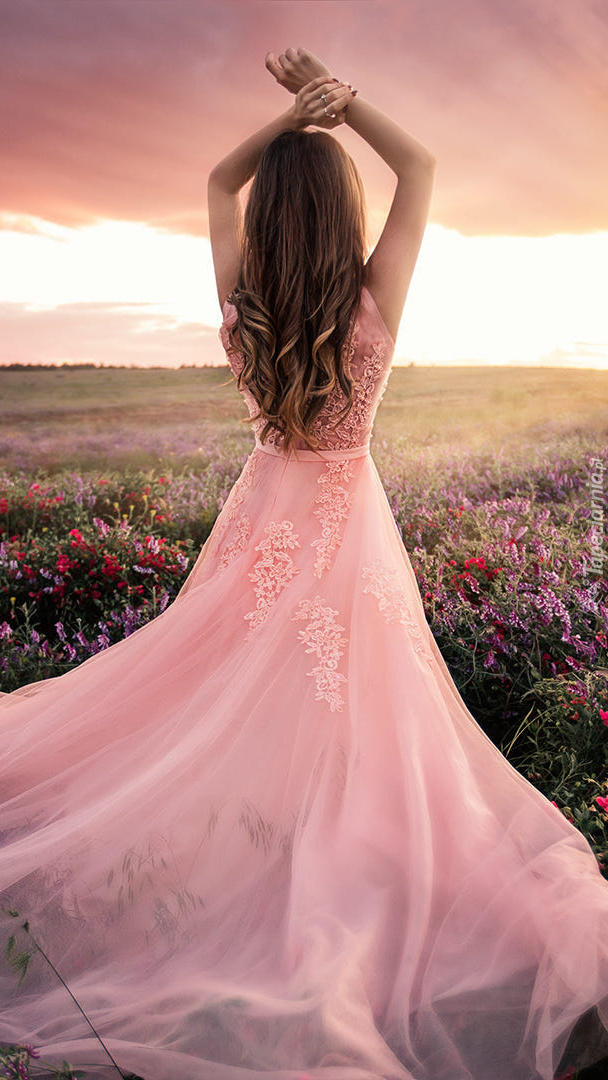 Kobieta w różowej sukni na łące