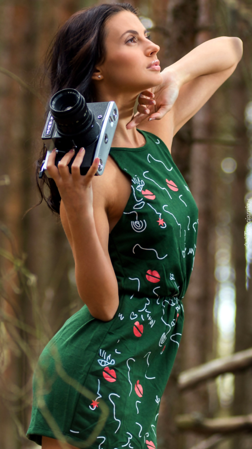 Kobieta w zielonej sukience i aparatem fotograficznym