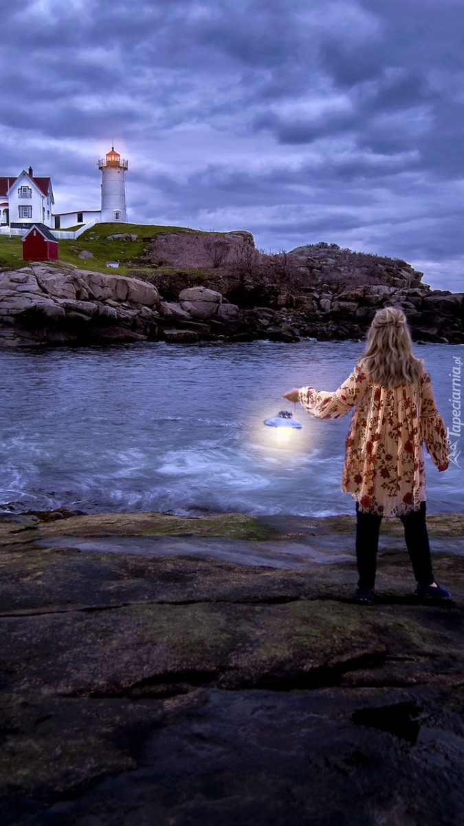 Kobieta z lampą i latarnia morska na skale