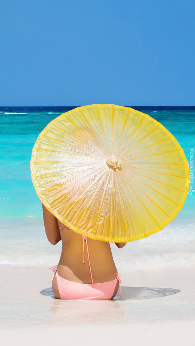 Kobieta z parasolką na letniej morskiej plaży