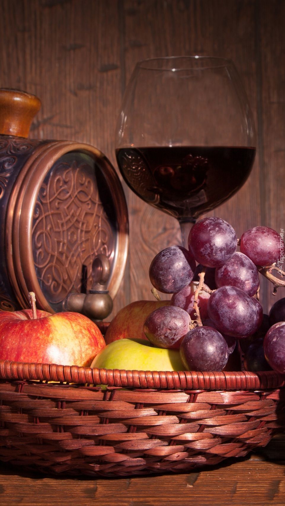Koszyk z owocami obok beczki i kieliszka wina