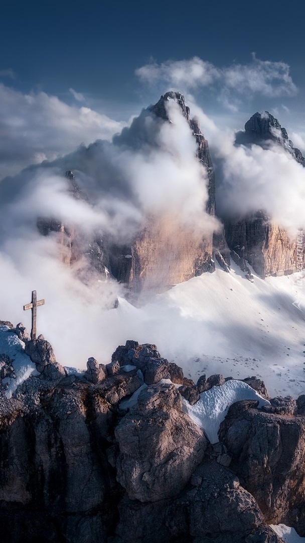 Krzyż na skałach na tle zamglonych Dolomitów