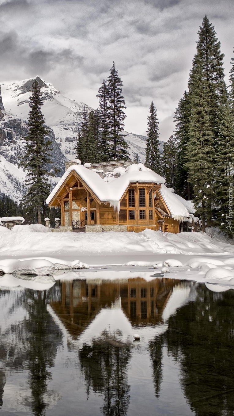 Letniskowy domek nad jeziorem w górach w zimowej scenerii
