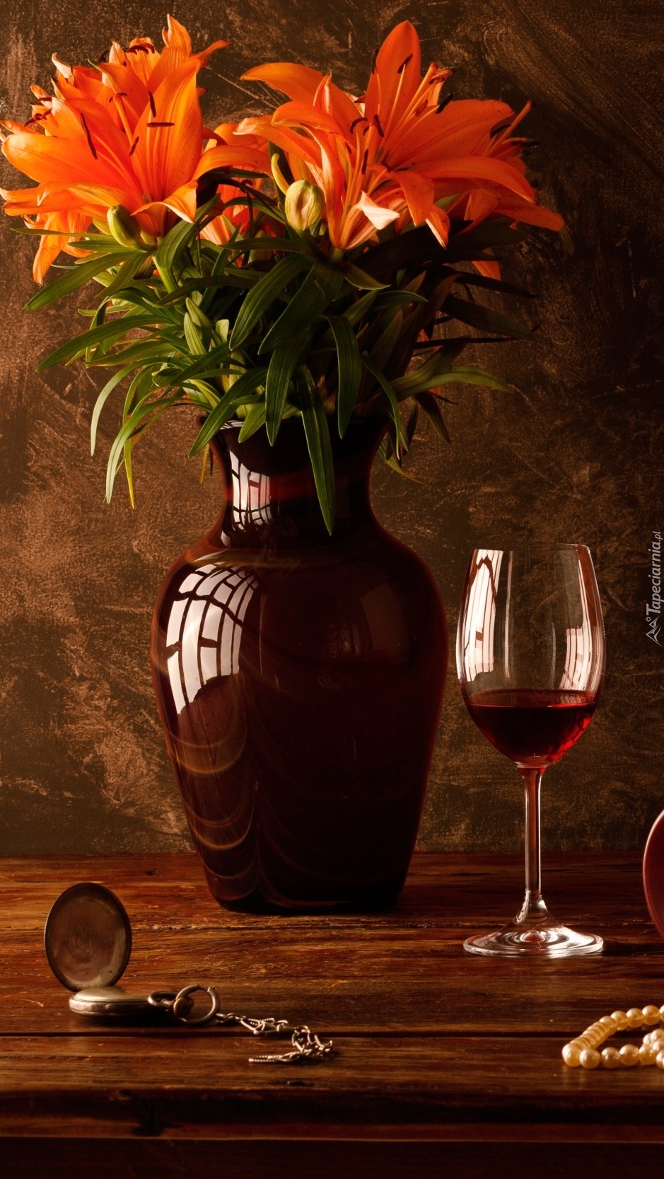 Lilie w wazonie obok kieliszka wina i zegarka