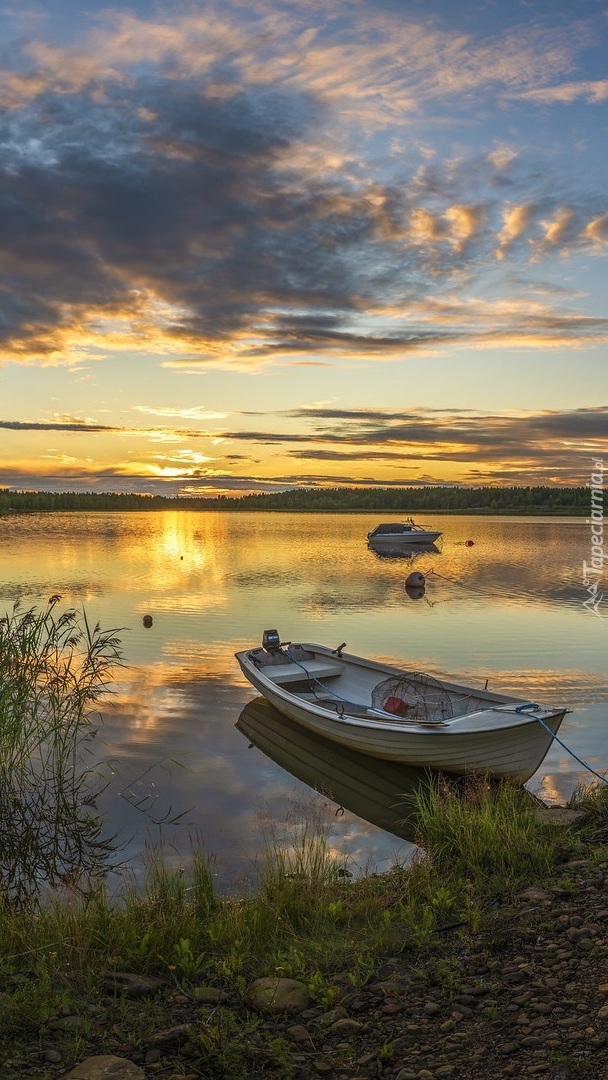 Łódka na brzegu jeziora o zachodzie słońca