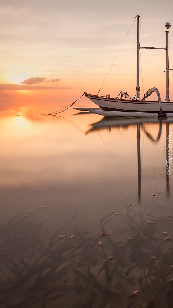 Łódka na morzu o wschodzie słońca