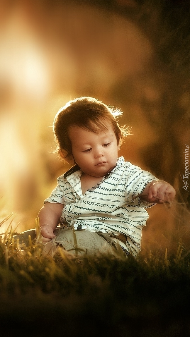 Małe dziecko siedzące na trawie