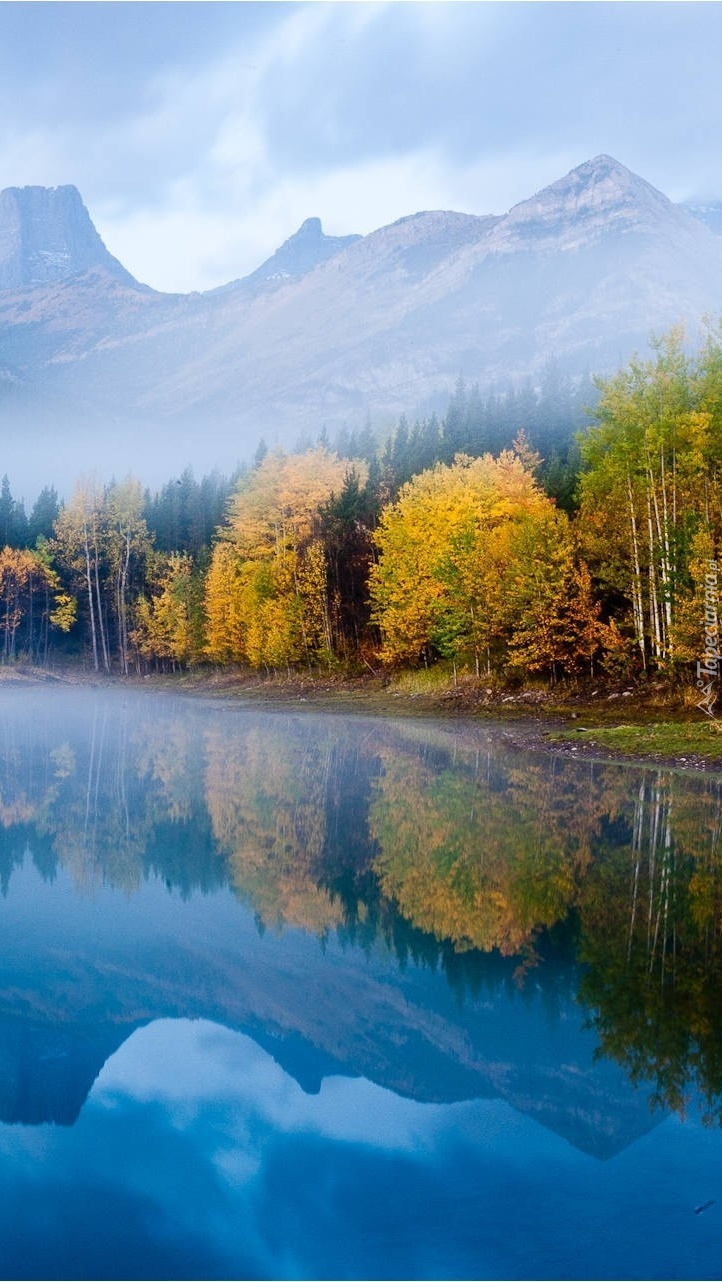 Mgliste góry i las jesienny odbite w jeziorze