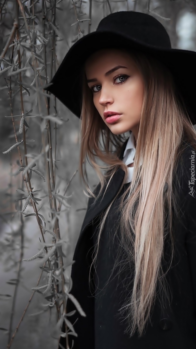 Modelka o długich blond włosach w czarnym kapeluszu