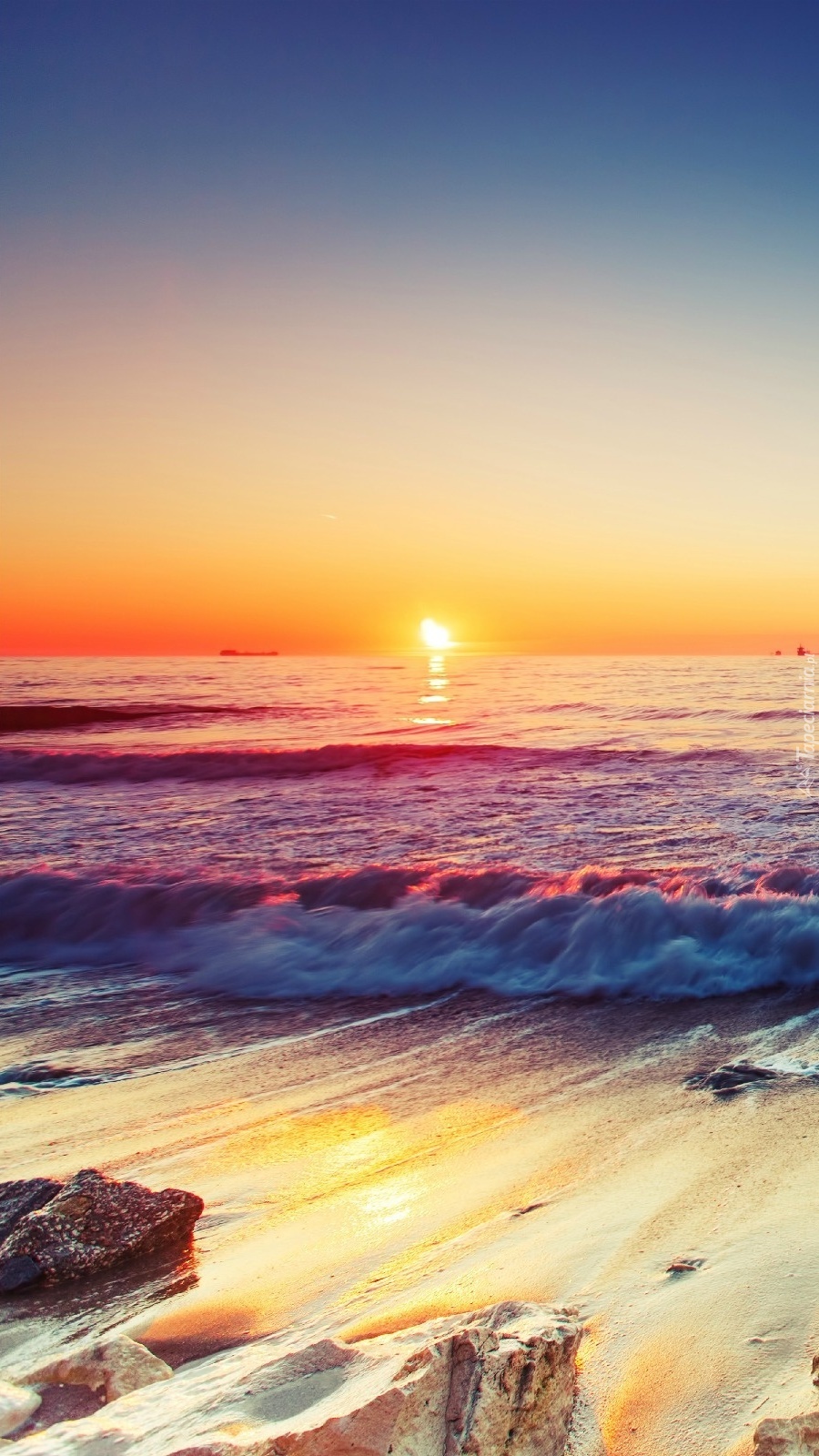 Morskie fale na kamienistej plaży o zachodzie słońca