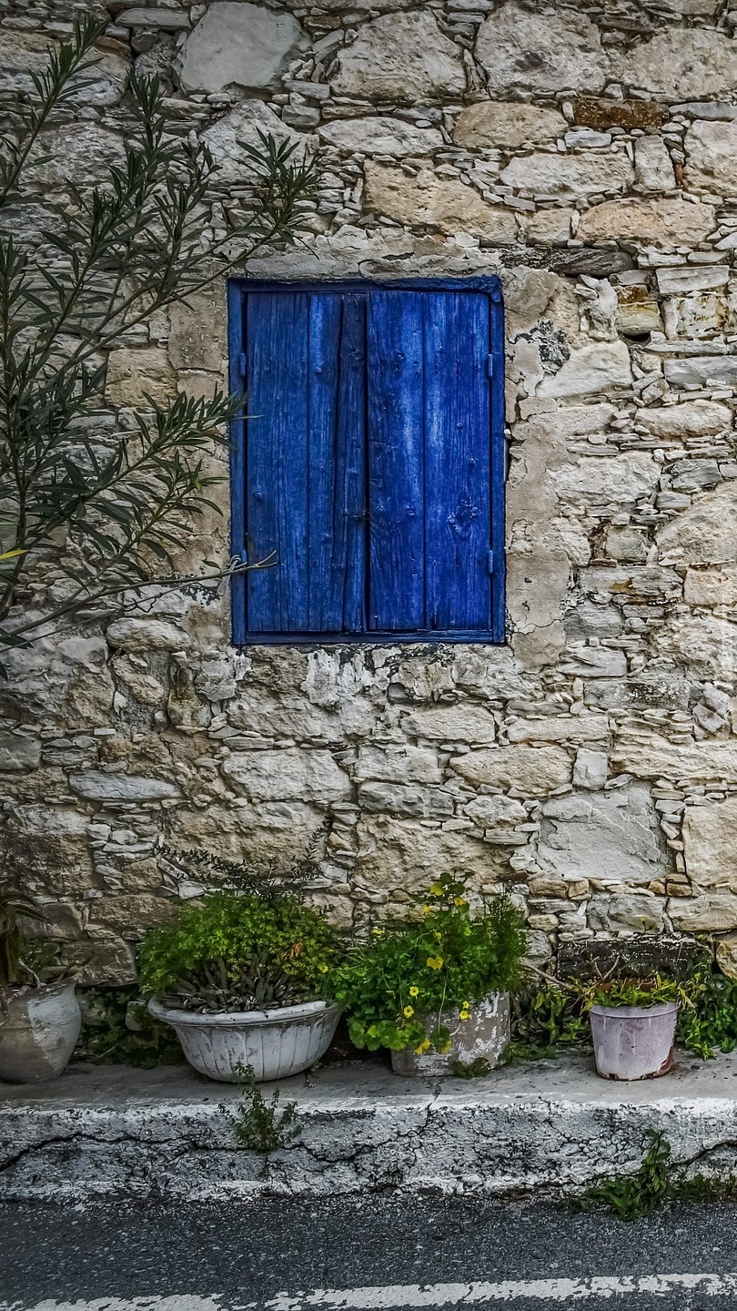 Niebieskie okiennice w kamiennej ścianie