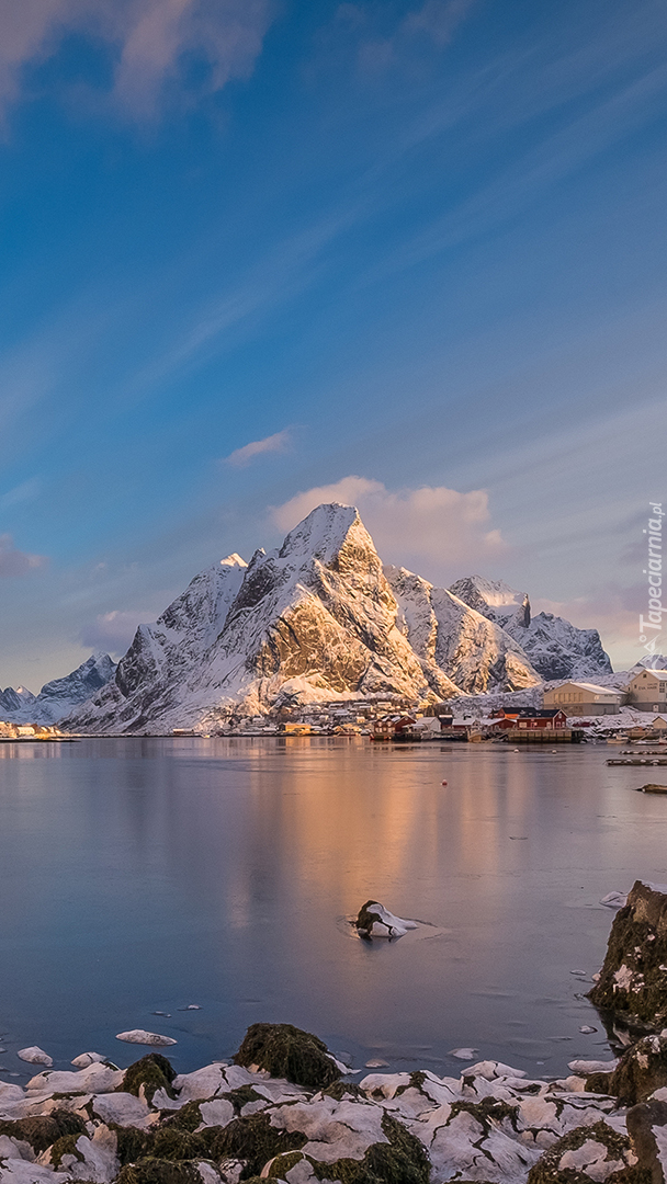 Norweska wioska nad jeziorem u podnóża gór w zimowej szacie
