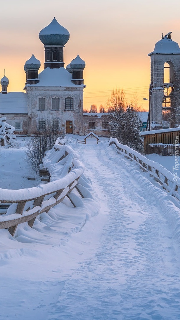 Ośnieżony most nad rzeką i cerkiew w tle