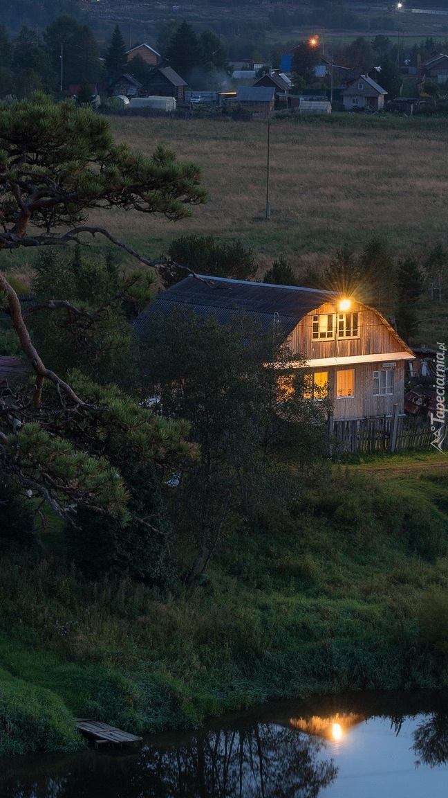 Oświetlony dom nad stawem