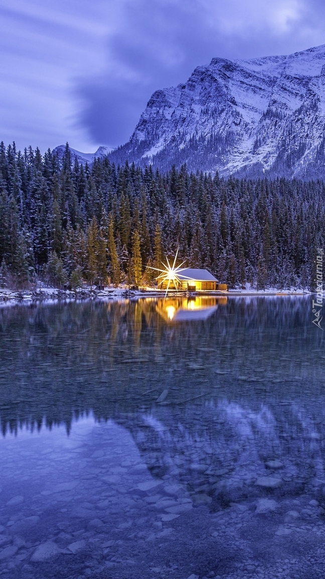 Oświetlony dom pod lasem nad jeziorem Lake Louise