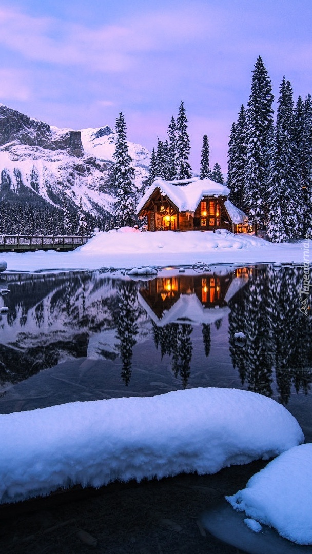 Oświetlony dom w śniegu na brzegu jeziora Emerald Lake