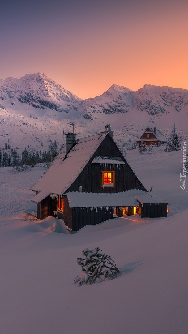 Oświetlony domek w górach zimą
