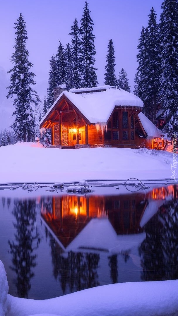 Oświetlony zaśnieżony dom nad jeziorem Emerald Lake