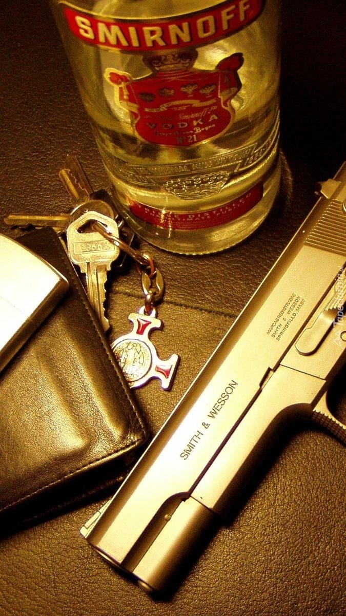 Pistolet obok butelki Smirnoffa