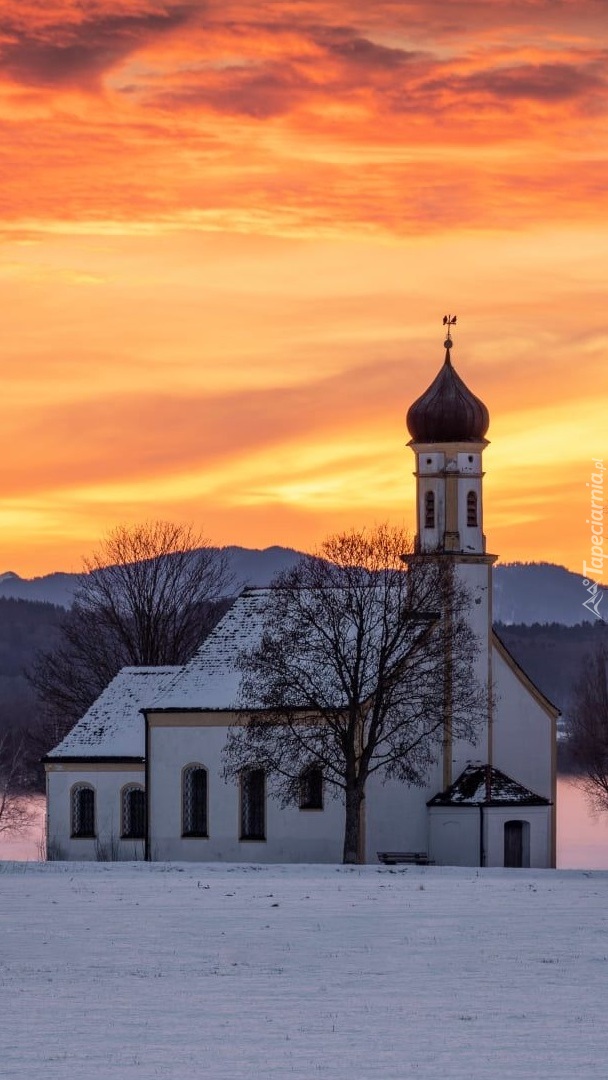 Pomarańczowe niebo nad ośnieżonym kościołem