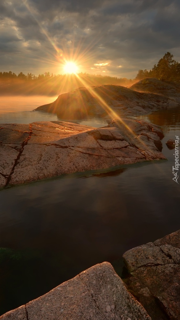 Promienie słońca nad skałami w jeziorze
