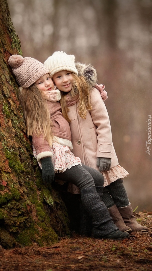 Pzrytulone dziewczynki opierają się o drzewo