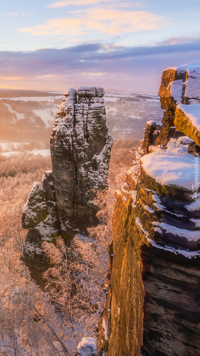 Rozświetlone ośnieżone skały i drzewa