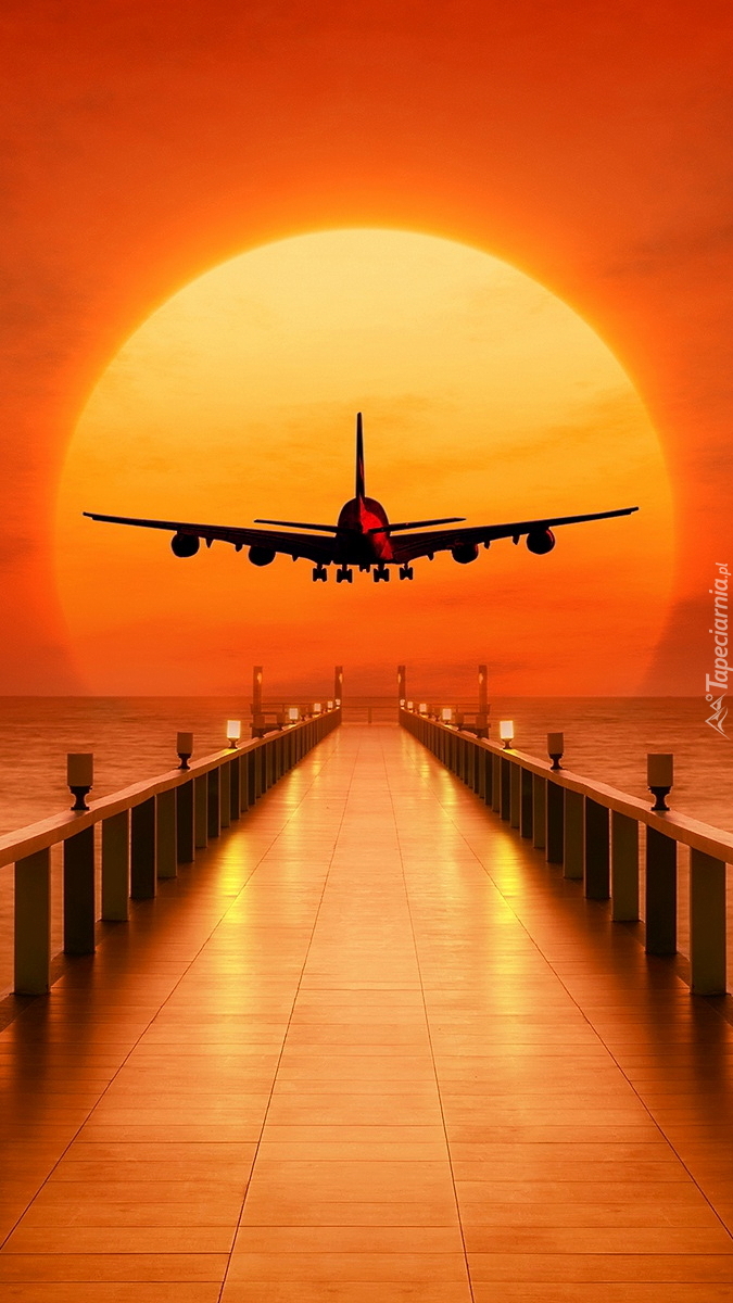 Samolot nad molem w zachodzącym słońcu