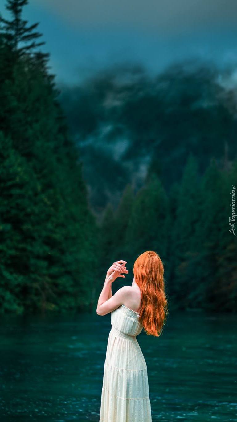 Samotna kobieta nad rzeką w lesie