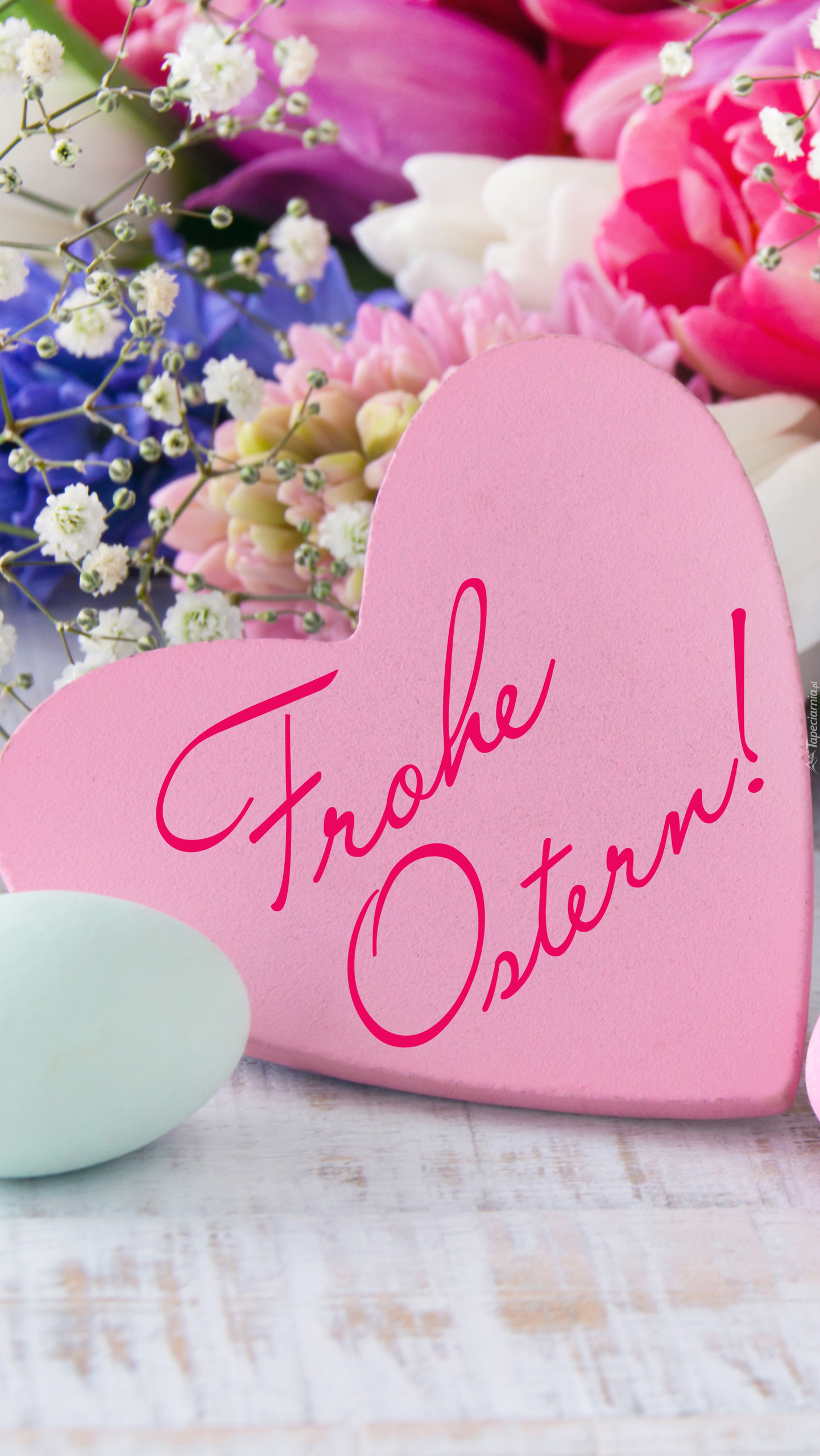 Serce z napisem Frohe Ostern obok kwiatów