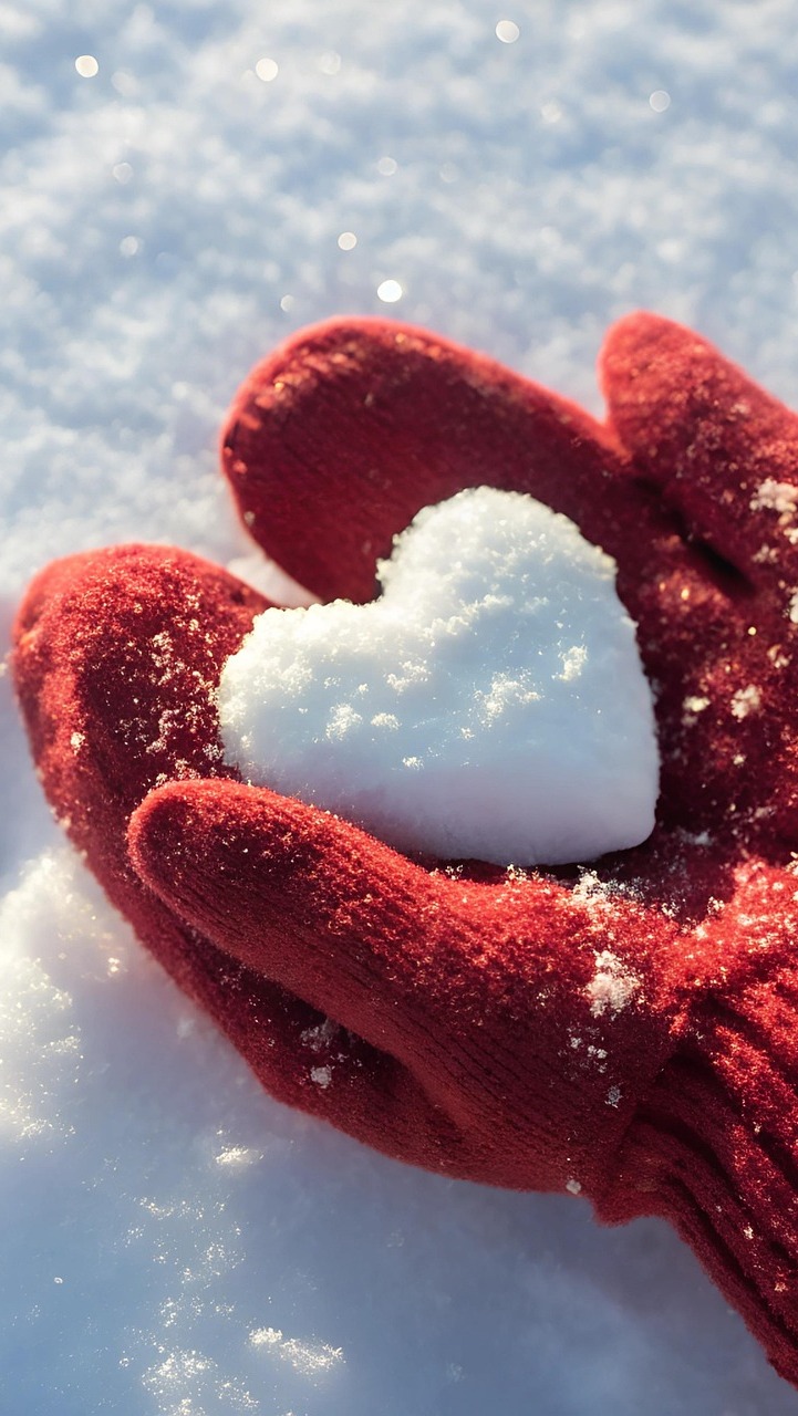 Serce ze śniegu na dłoniach w czerwonych rękawiczkach