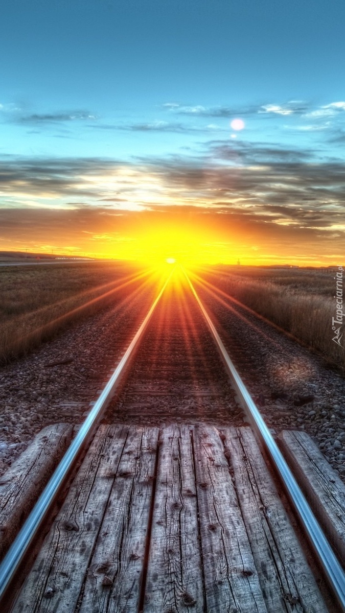 Słońce oświetlające tory kolejowe