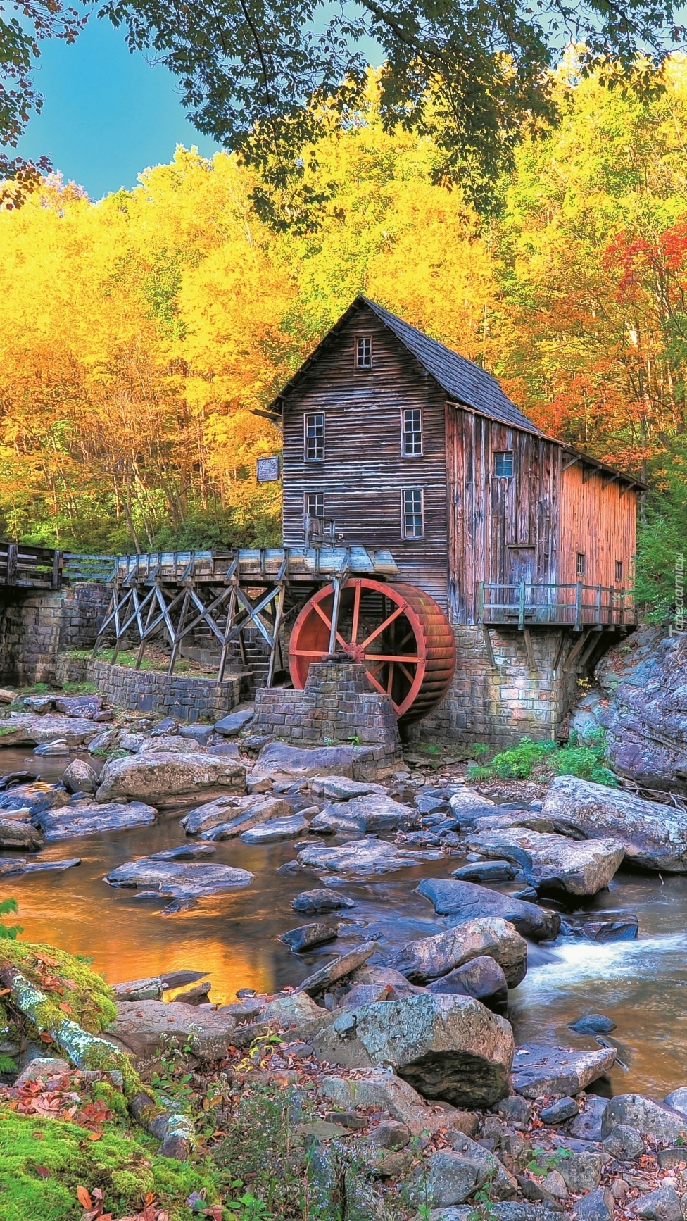 Stary drewniany młyn nad rzeką jesienią