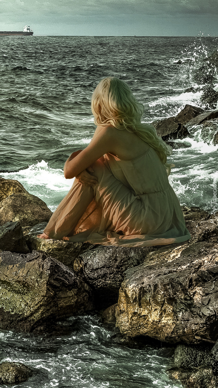 Statki na morzu i kobieta siedząca na kamieniach