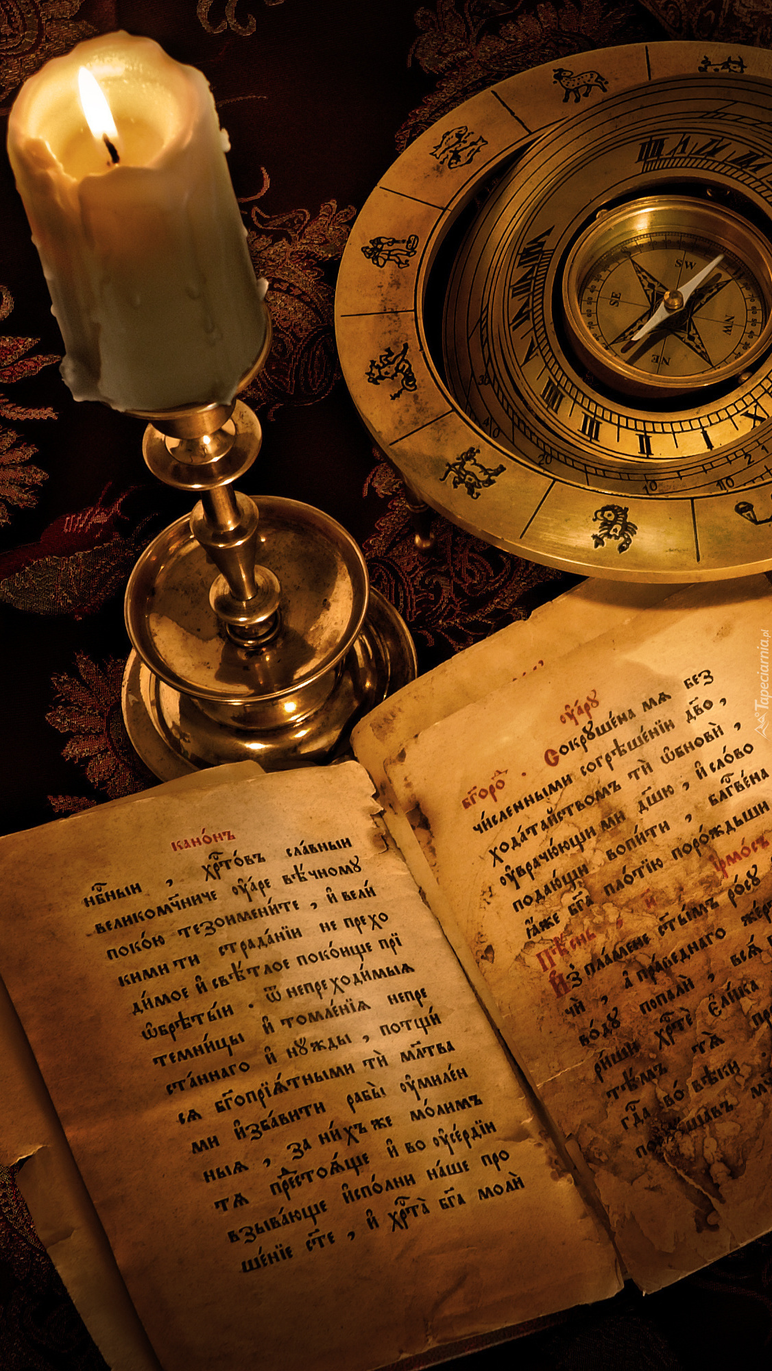 Świeca obok kompasu i starej książki